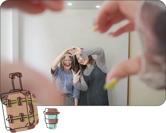 仕事もプライベートも充実を示す写真。仲の良い女性スタッフ2人が笑顔で自撮り（手でハートマーク）をしており、良好なワークライフバランスや人間関係を表現。