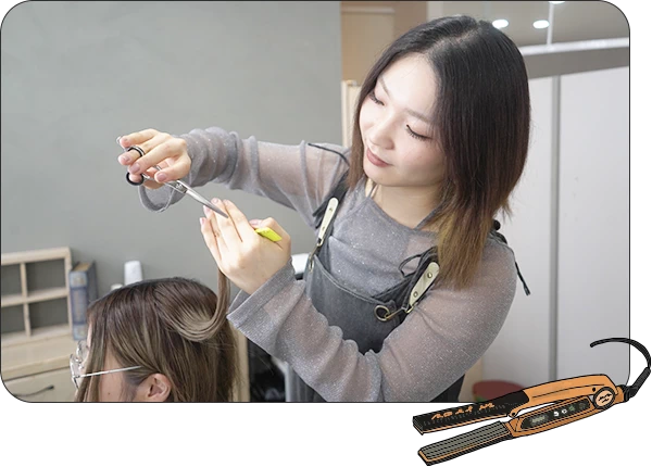 高い技術が身に付くことを示す写真。スタイリストがお客様の髪をハサミとコームを使って丁寧にカットしている様子。専門的なレッスンや実践的な経験を通じてスキルアップできることを表現。